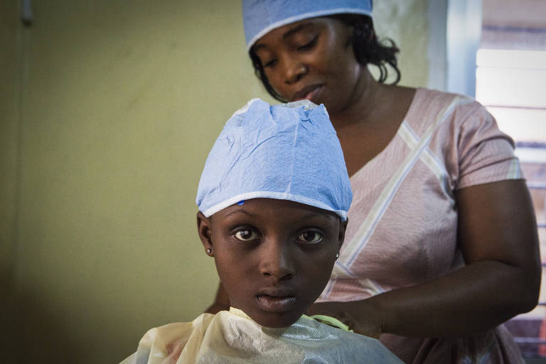 Aminata Conteh, 8, puts on a hospital gown before undergoing eye surgery, in Freetown, Sierra Leone.