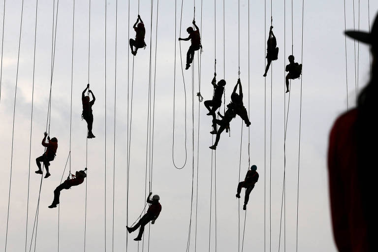 People climb after jumping off a bridge, which has a height of 30 meters, in Hortolandia