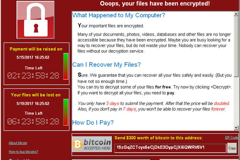 Reprodução de tela de computador mostra fundo vermelho com texto explicando como uma pessoa pode fazer o pagamento em bitcoins para recuperar acesso à máquina. No canto superior esquerdo há o desenho de um cadeado