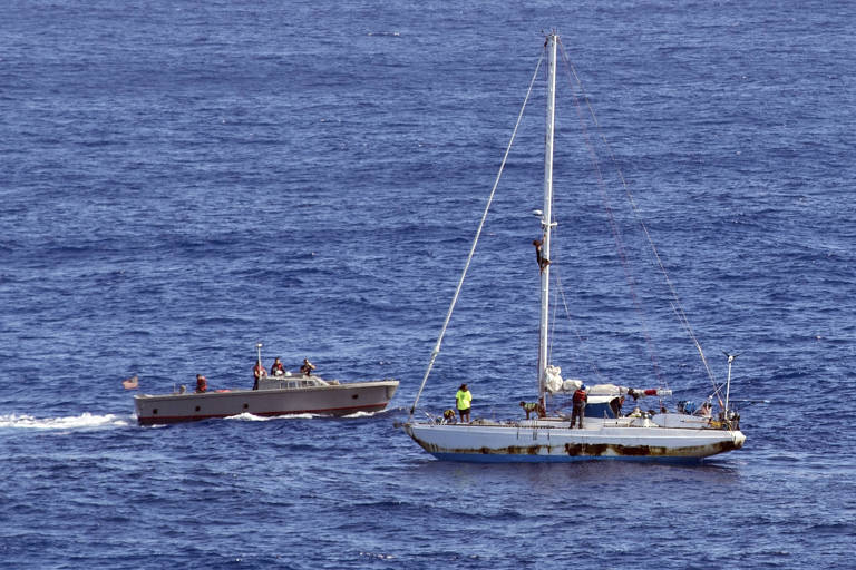 O barco USS Ashland, da Marinha americana (esq.) se aproxima do barco onde estavam as duas mulheres 