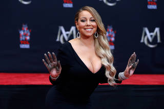 Singer Carey shows her hands after placing them in cement in the forecourt of the TCL Chinese theatre in Los Angeles