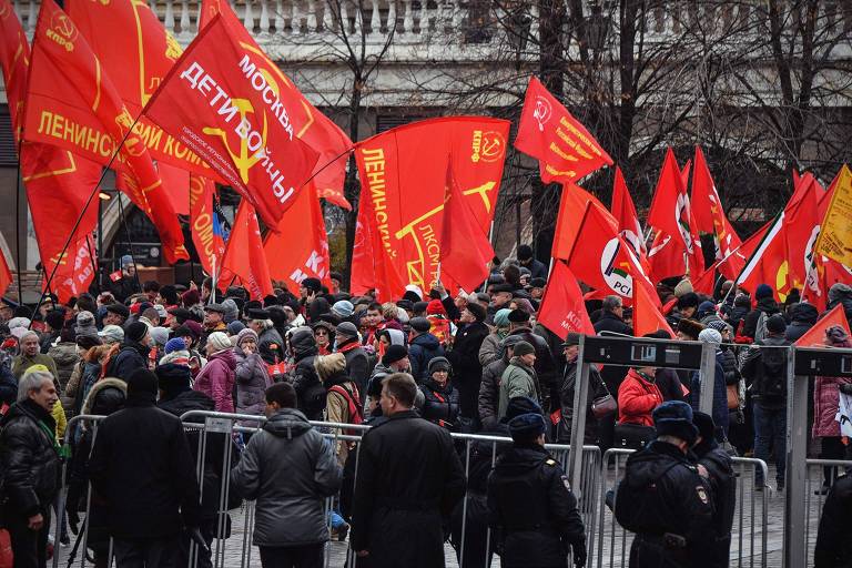 Partidários comunistas russos acenam bandeiras enquanto se reúnem na entrada da Praça Vermelha em Moscou