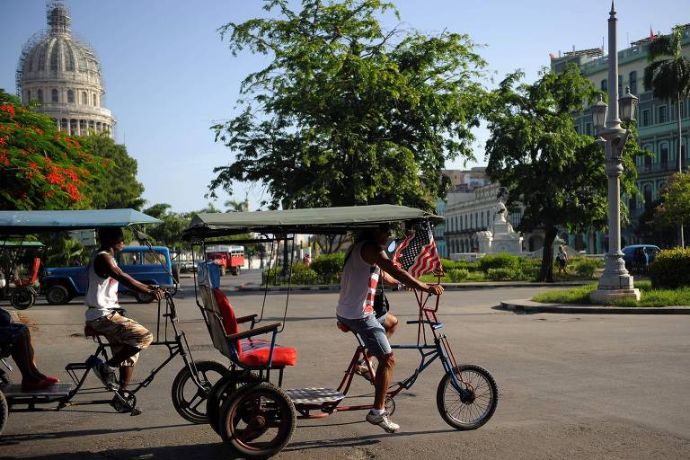 Bicitxi enfeitado com a bandeira dos EUA passa por praa de Havana