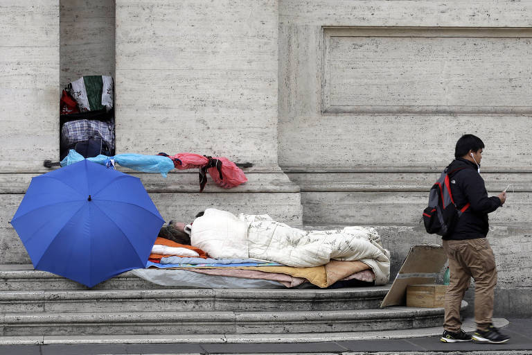 Homem passa por sem-teto dormindo em escadaria de prdio em Roma (Itlia)