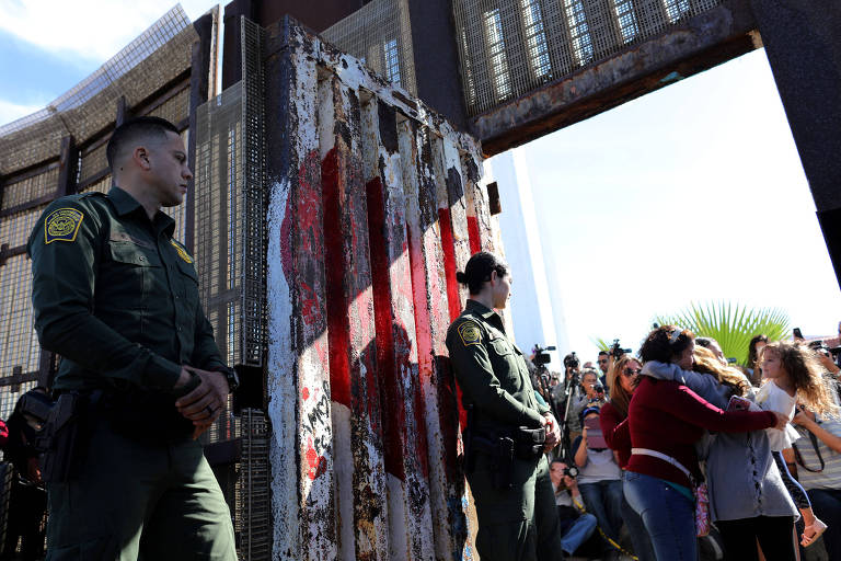 Guardas de fronteira observam famlia se abraando na abertura do porto entre San Diego e Tijuana