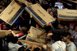 Shoppers reach out for television sets as they compete to purchase retail items on Black Friday at a store in Sao Paulo