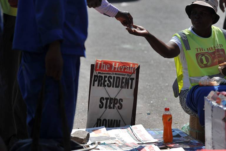 Homem vende jornais em Harare, capital do Zimbbue, com a notcia da renncia do ditador Mugabe