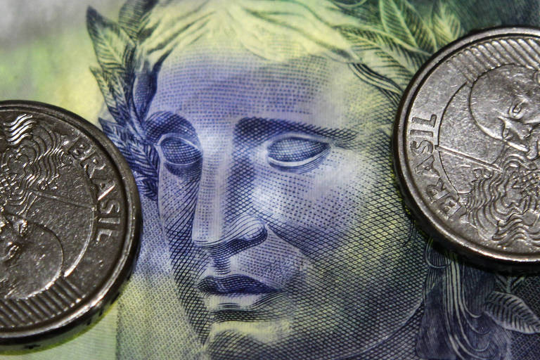 Cédula de dinheiro brasileiro com moedas e cores da bandeira do Brasil