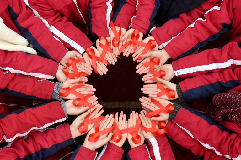 Estudantes seguram fitas vermelhas durante um evento para marcar o Dia Mundial de Combate à Aids em uma escola secundária em Hefei, província de Anhui, na China