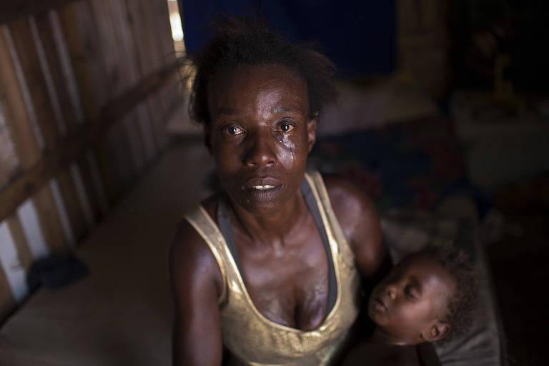 Moradora da favela carioca Jardim Gramacho chora com bebê no colo ao contar que foi cortada do programa social Bolsa Família