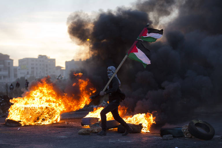 Manifestante com bandeiras da Palestina em Ramallah, na Cisjordnia
