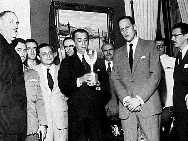 João Havelange ao lado do então presidente e amigo Juscelino Kubitschek, que segura a Taça Jules Rimet em uma recepção aos jogadores da seleção brasileira, campeões mundiais.