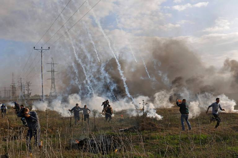 Palestinos desviam de bombas de gs lacrimogneo atiradas por foras de Israel na faixa de Gaza