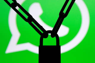 A photo illustration shows a chain and a padlock in front of a displayed Whatsapp logo