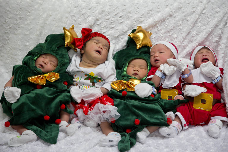 Recém-nascidos dormem vestidos com roupas natalinas