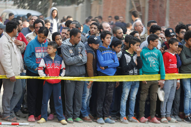 Pessoas observam local de ataque em igreja cristã no distrito de Helwan, no Cairo (Egito)