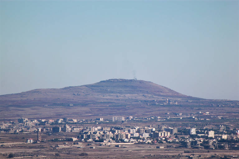 Fumaça escura sobe de vilarejo sírio afetado pela guerra civil próximo às colinas de Golã