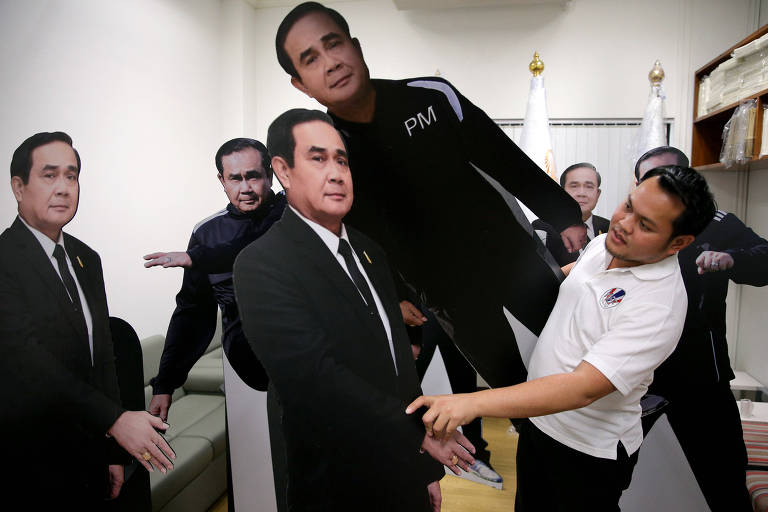 Funcionário do governo organiza figuras de papelão mostrando o líder da junta militar da Tailândia, general Prayuth Chan-ocha, em Bangcoc
