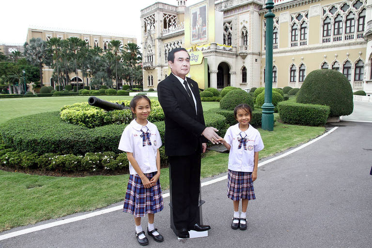 Crianças dão a mão a figura de papelão do líder da Junta Militar da Tailândia, general Prayuth Chan-ocha, em Bangcoc