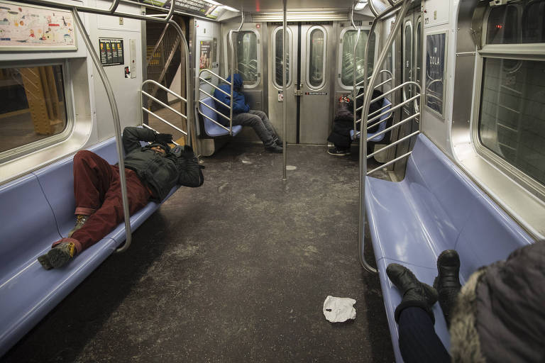 Sem-teto dormem de madrugada em trem da linha E do metrô de Nova York em noite de frio intenso