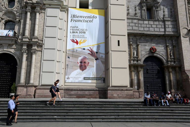 Pedestres passam por cartaz anunciando a visita do papa Francisco na Catedral de Lima, no Peru