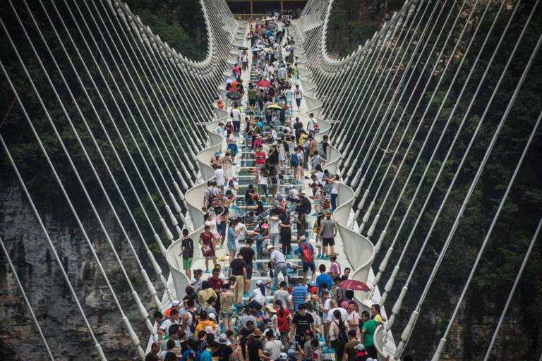 Visitantes sobre a ponte de vidro mais alta e comprida do mundo, no parque Zhangjiajie, na China