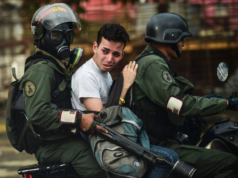 Guardas nacionais levam manifestante preso em moto durante protesto em Caracas