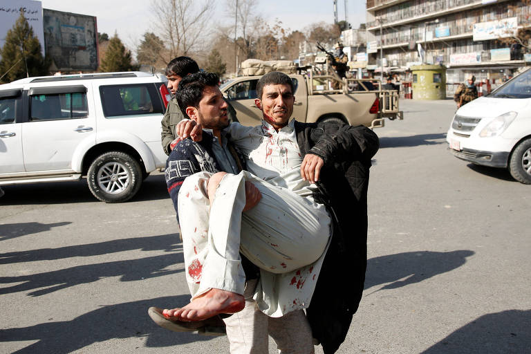 Um homem ferido é levado para receber os primeiros-socorros após explosão de ambulância em Cabul, no Afeganistão