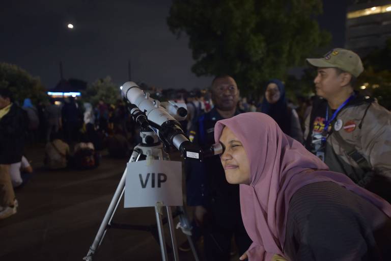 Mulher da Indonésia usa telescópio para ver a superlua azul de sangue em Jacarta 