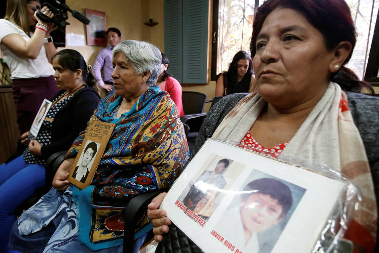 Com fotos de seus filhos nas mãos, três mães de vítimas de grupo de extermínio ligado a Alberto Fujimori protestam sentadas durante uma entrevista coletiva em San José, na Costa Rica