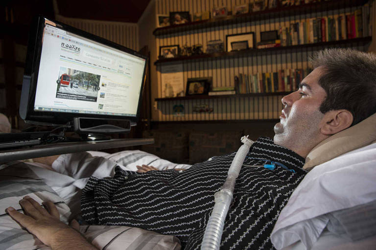 O economista Ricky Ribeiro deitado na cama observa tela de computador que mostra a página principal do site Mobilize