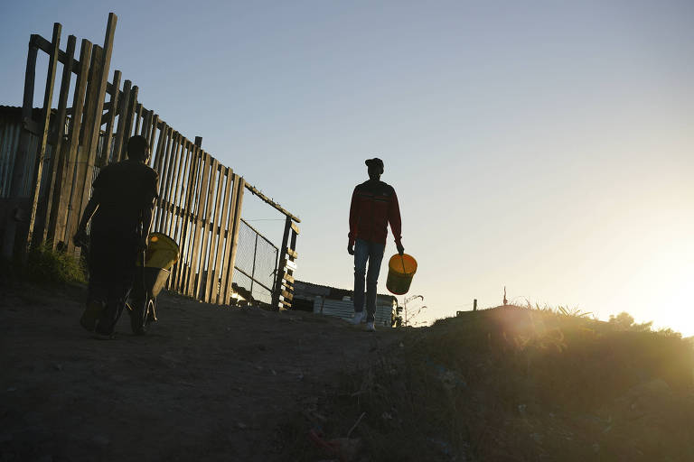 Homem caminha com balde em região de seca na Cidade do Cabo