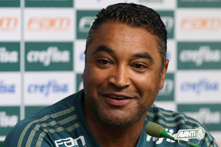 O técnico Roger Machado, do Palmeiras, sorri em frente ao microfone, durante coletiva de imprensa concedida na Academia de Futebol