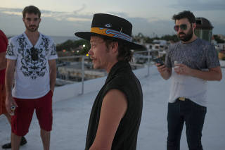 Brock Pierce, center, with Josh Boles, left, and Matt Clemenson on the roof of the Monastery Art Suites, which they have rented out as a headquarters for their cryptocurrency business, in San Juan, in Puerto Rico.