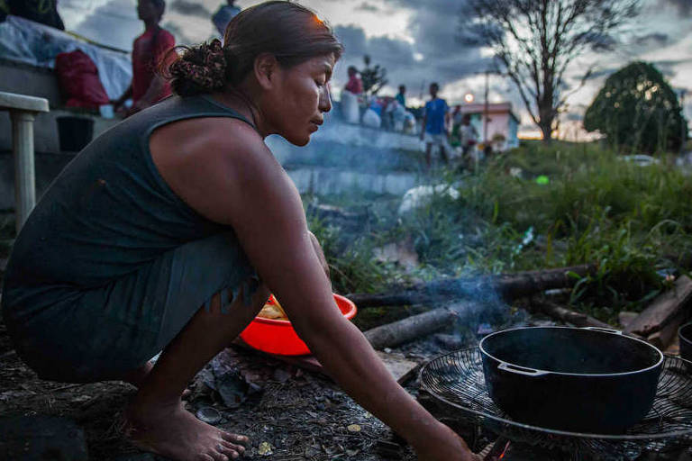 Kenia Sapatta, índia venezuelana, prepara comida em terreno baldio em Pacaraima (RR)