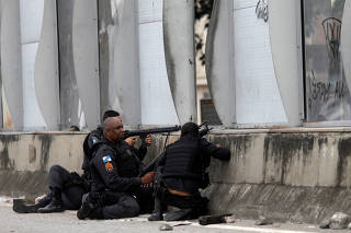 Policemen take up positions during an operation against drug dealers near the Mare slum complex in Rio de Janeiro