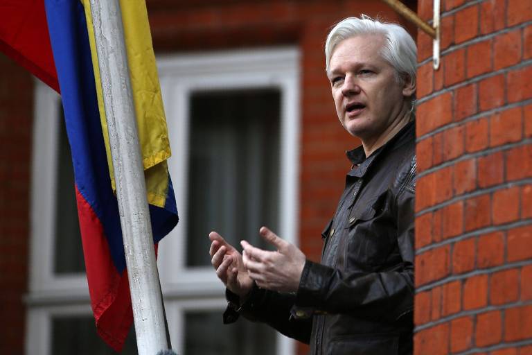 O fundador do WikiLeaks, Julian Assange, fala a seus seguidores na sacada da casa onde fica a embaixada do Equador em Londres; à esquerda do ativista, um mastro com a bandeira equatoriana