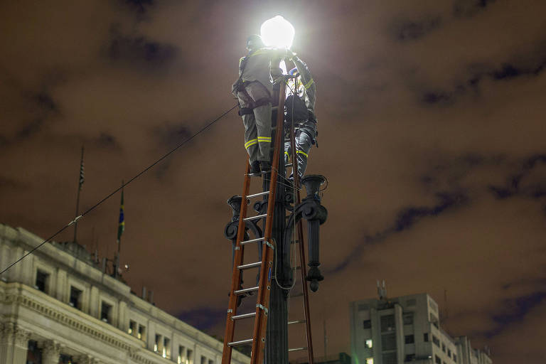 Funcionários substituem lâmpadas em poste no viaduto do Chá no centro de São Paulo

