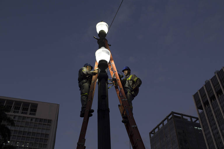 Funcionários substituem lâmpadas em poste no viaduto do Chá no centro de São Paulo