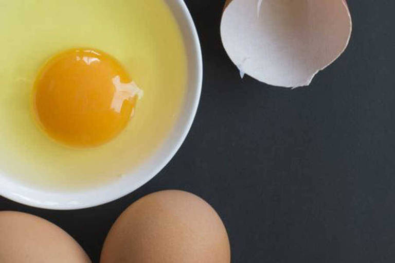 Imagem mostra dois ovos, uma casca quebrada e o conteúdo de um ovo (clara e gema) em um recipiente