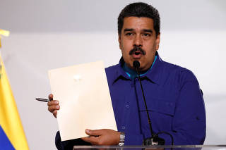 Venezuela's President Nicolas Maduro holds a document as he talks to the media before an event with supporters of Somos Venezuela (We are Venezuela) movement in Caracas