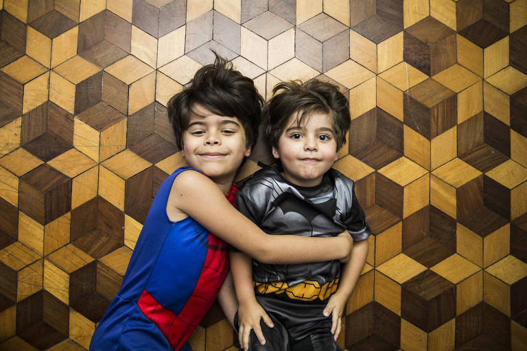 João, de sete ano, vestido de Homem-Aranha, abraça o irmão, Heitor, de 3, vestido de de Batman