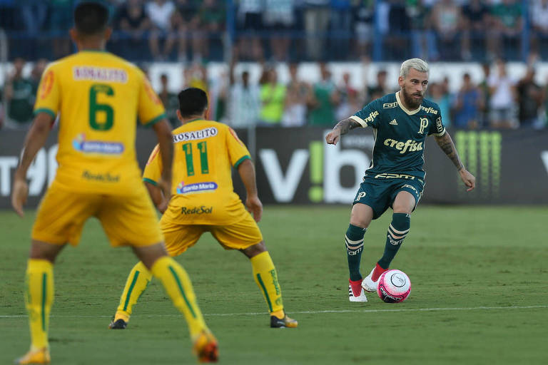 Lucas Lima, do Palmeiras, anda com a bola em frente a dois jogadores da equipe adversária, em jogo contra a equipe do Mirassol, neste sábado (10)