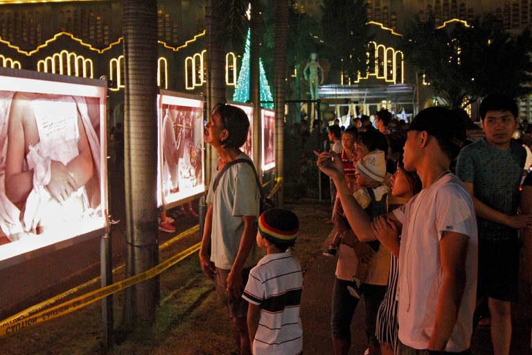 Frequentadores da igreja católica Nossa Senhora do Perpétuo Socorro em Manila, nas Filipinas, observam fotos expostas de vítima de 15 anos morta na guerra as drogas promovida nas Filipinas pelo presidente Rodrigo Duterte