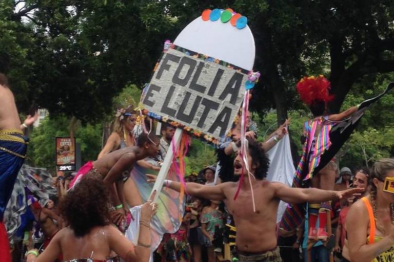 Integrantes do Orquestra Voadora desfilam com faixas dizendo "Apesar de voc,  Carnaval" 