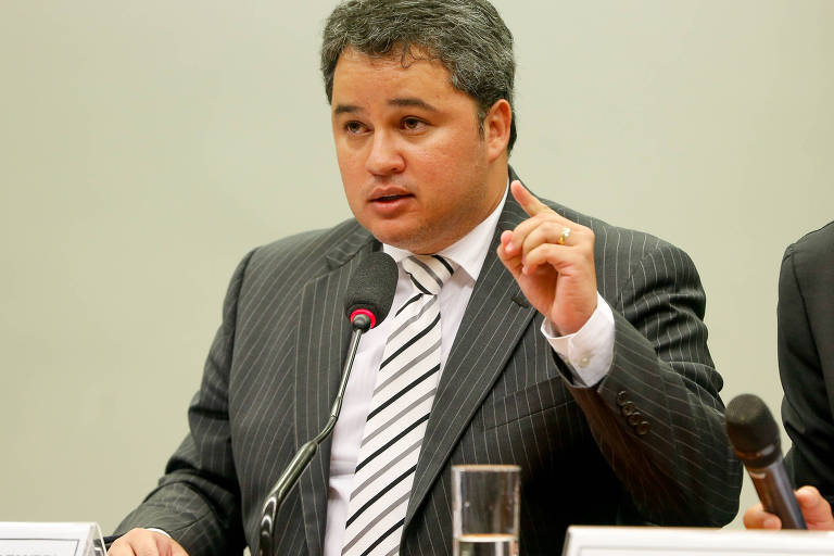 O deputado federal Efraim Filho fala ao microfone. Está de terno cinza, camisa branca e gravata listrada