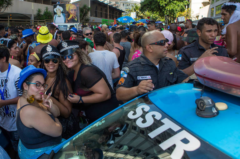 Carro da polícia em meio a foliões na região de Ipanema, no Rio