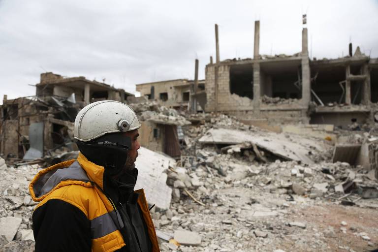 Membro dos capacetes brancos observa prédio destruído em Medeira, na Síria; Irã vê reconstrução como oportunidade de recuperar gastos de ajuda a Assad