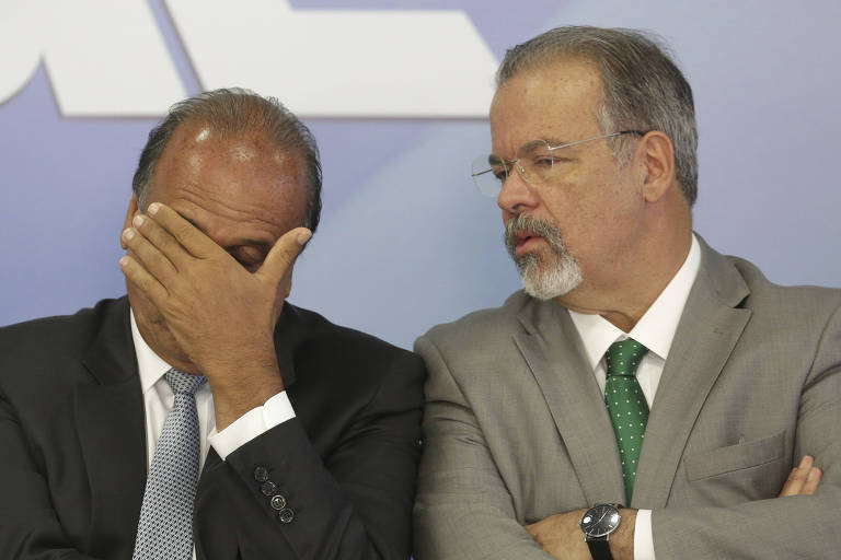 O governador do Rio, Luiz Fernando Pezao, leva a mão ao rosto; ao lado, o ministro da Defesa, Raul Jungmann