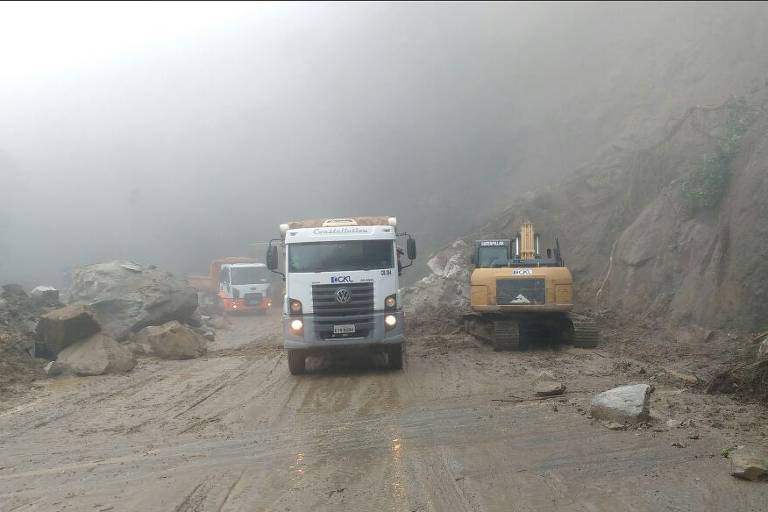Caminhões e tratores trabalhando para desobstruir a rodovia Mogi-Bertioga